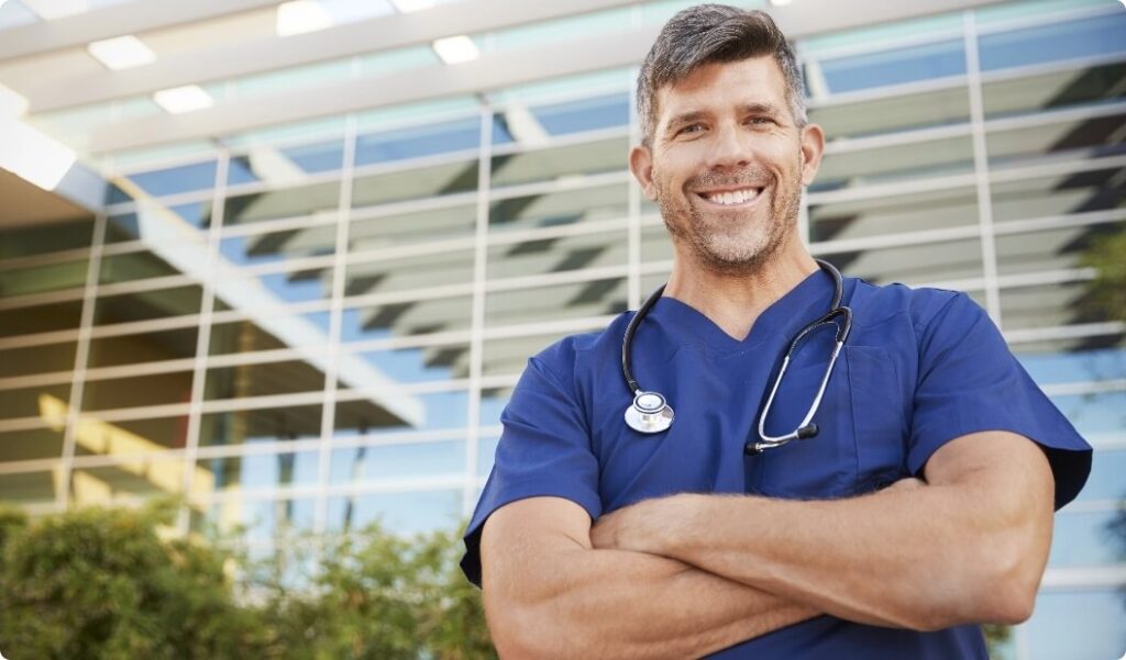 happy-male-healthcare-worker-smiling-to-camera-out-2021-08-26-16-14-59-utc@2x